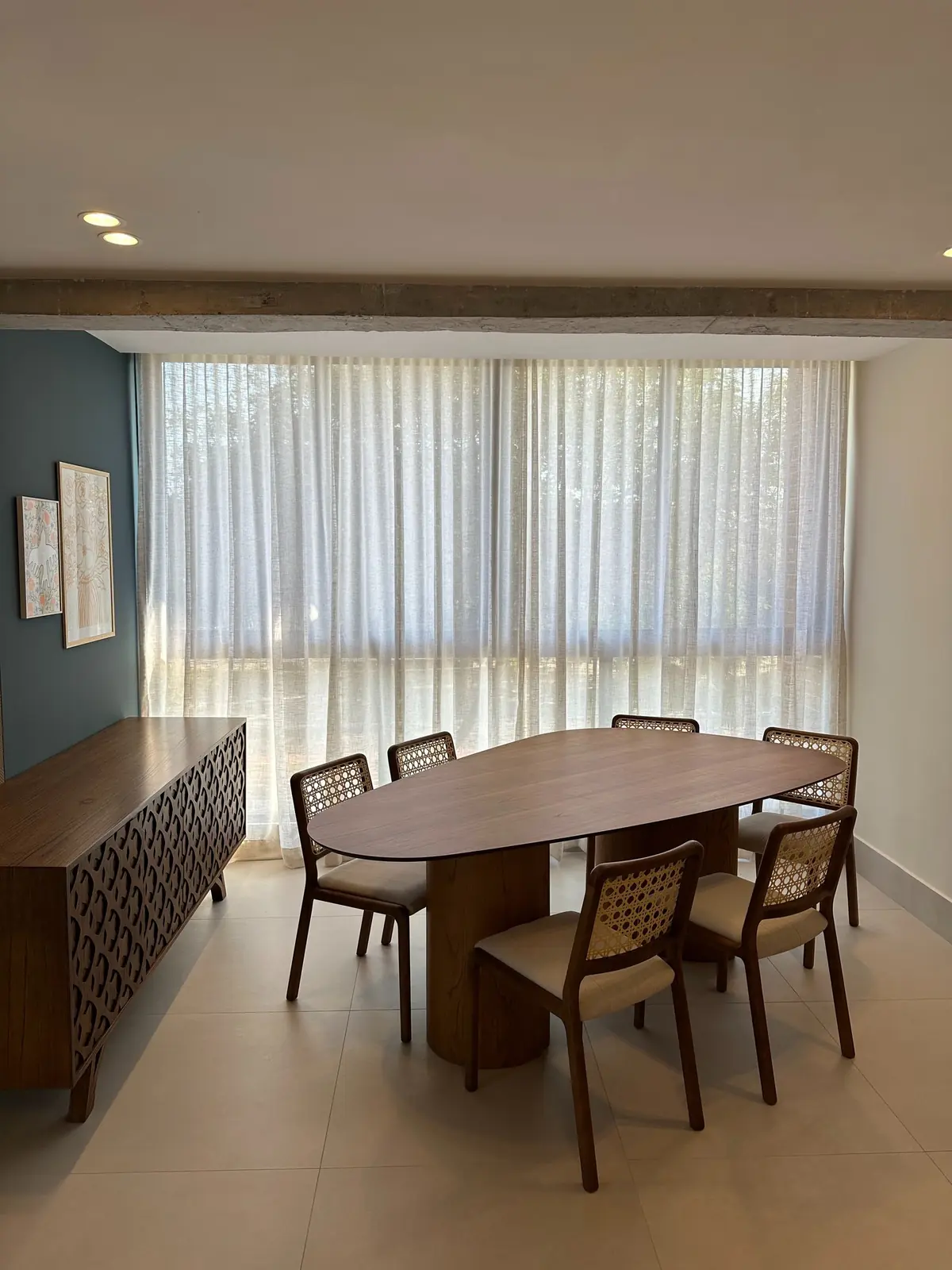 Sala de jantar com cortina de voil branca instalada em trilho, do teto ao chão