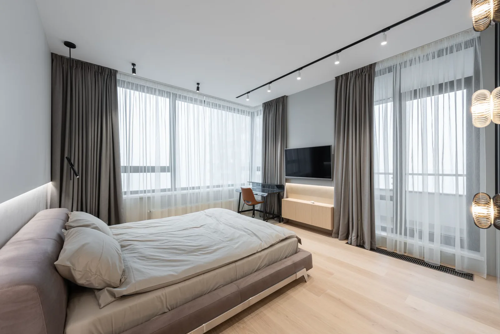 Quarto claro de dia, com cortina de voil e tecido mais fechado em trilho no teto, e a luz da janela entrando
